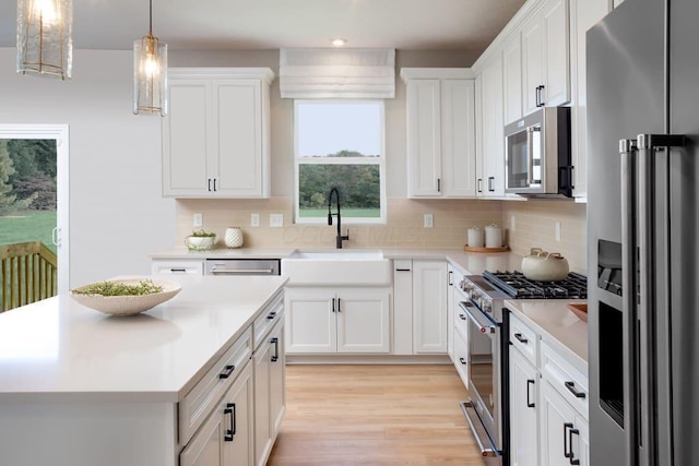 kitchen featuring a sink, decorative backsplash, light countertops, white cabinets, and appliances with stainless steel finishes