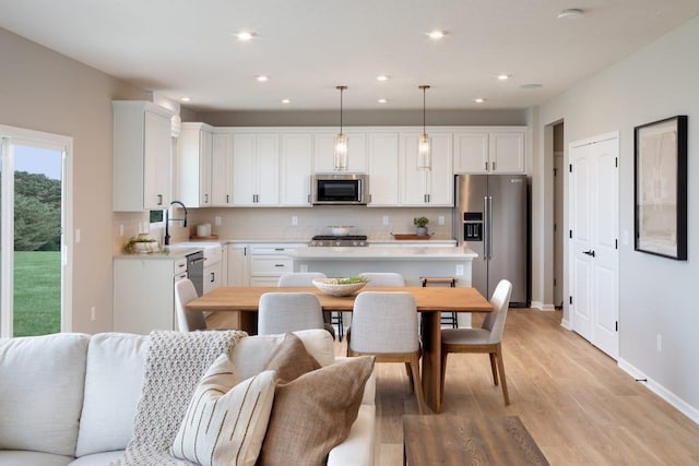 kitchen with a sink, stainless steel appliances, light countertops, and white cabinets