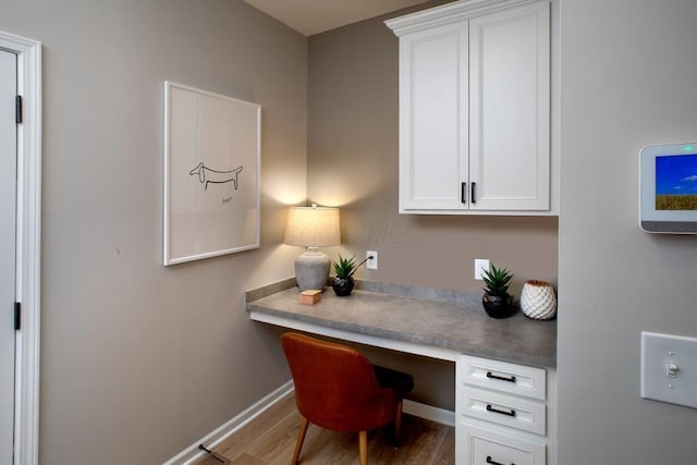 home office with built in desk, wood finished floors, and baseboards