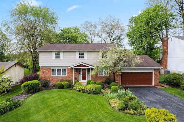 view of front of house with a front yard, brick siding, an attached garage, and aphalt driveway