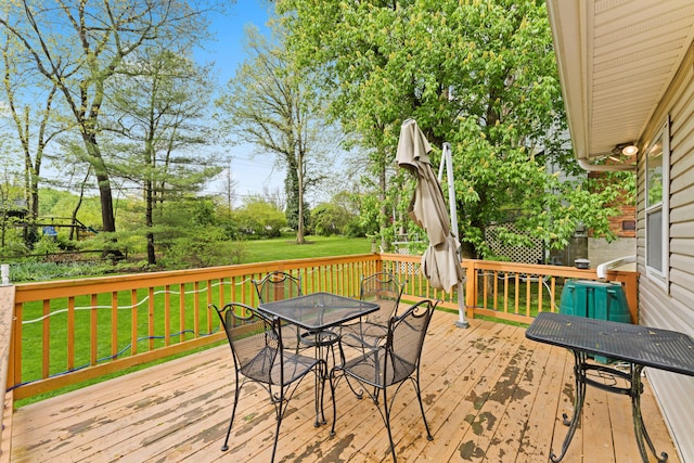 wooden deck featuring a lawn and outdoor dining space