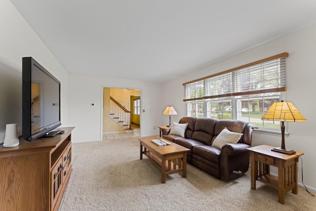 living area with stairway, light carpet, and baseboards