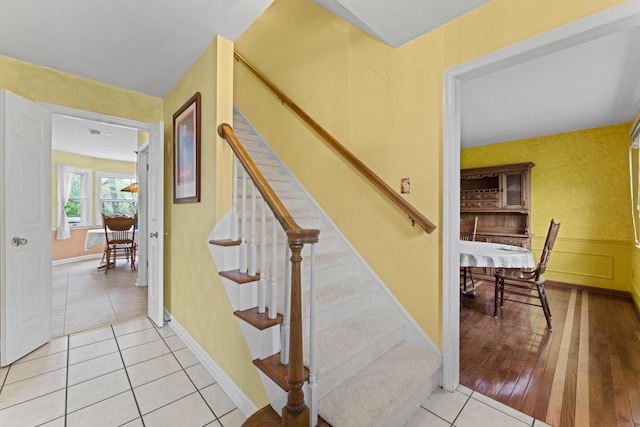 stairway featuring tile patterned floors and a wainscoted wall