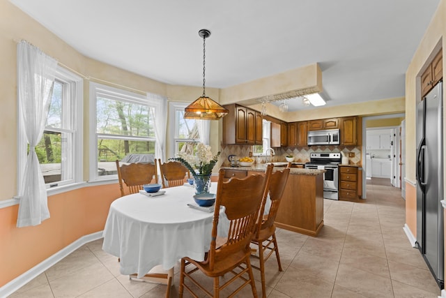 dining room featuring light tile patterned floors, plenty of natural light, and baseboards