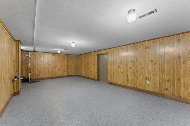finished below grade area with a textured ceiling, visible vents, and baseboards
