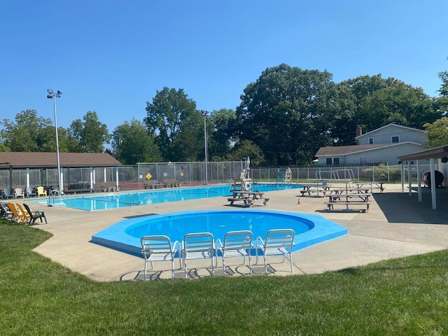 community pool with a patio area and fence