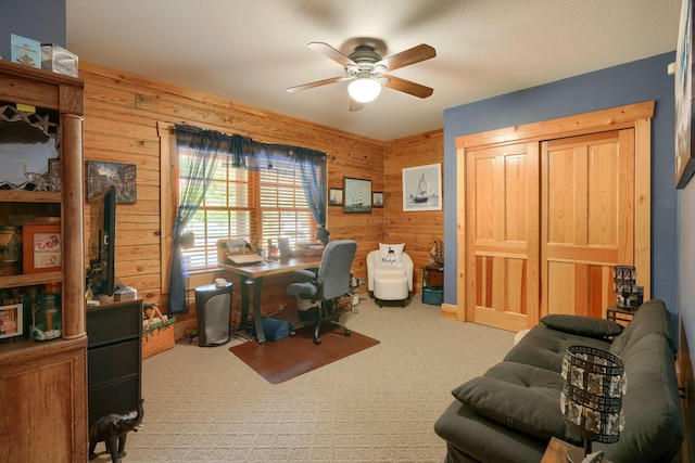 carpeted office featuring wood walls and a ceiling fan
