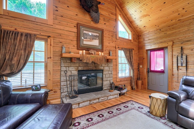 living room featuring a stone fireplace, wood walls, high vaulted ceiling, and wood finished floors