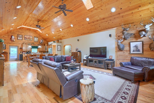 living room featuring light wood-type flooring, wood walls, and ceiling fan