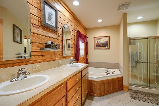 bathroom featuring a stall shower, a bath, tile patterned flooring, and a sink