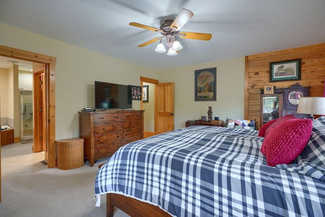 bedroom featuring a ceiling fan, wooden walls, and light colored carpet