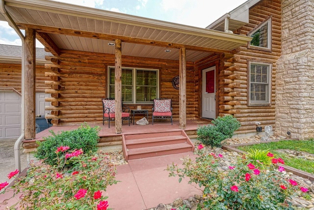 entrance to property featuring covered porch, log exterior, and a garage