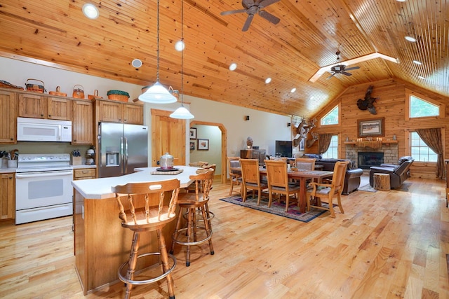 kitchen featuring a stone fireplace, a ceiling fan, arched walkways, and white appliances