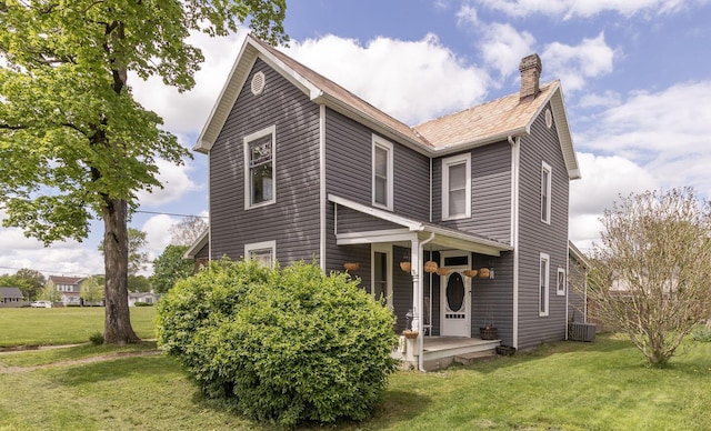 view of front of house with a chimney, a front yard, a porch, and central air condition unit