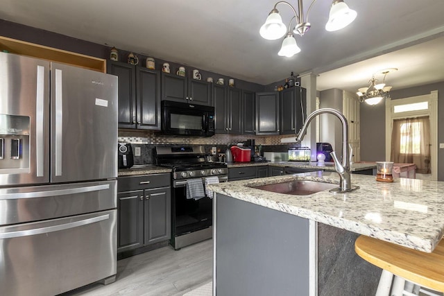 kitchen featuring light stone countertops, a kitchen breakfast bar, a chandelier, decorative backsplash, and stainless steel appliances