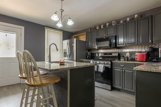 kitchen with stone counters, decorative backsplash, stainless steel appliances, and light wood-style flooring