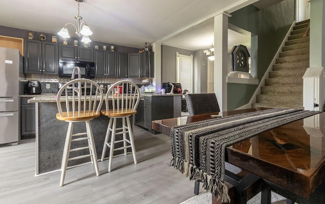 dining room with stairway, light wood finished floors, a notable chandelier, and vaulted ceiling