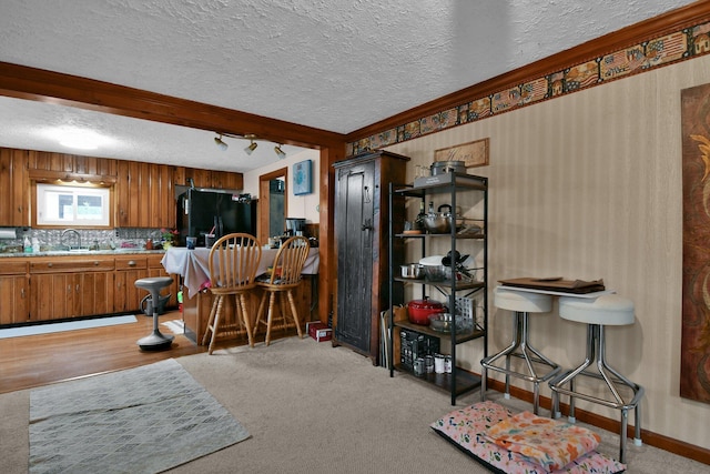 interior space with a sink, black fridge with ice dispenser, brown cabinets, light carpet, and light countertops