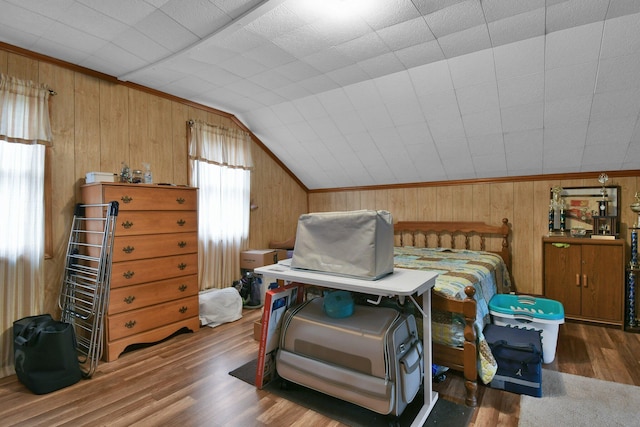 bedroom featuring lofted ceiling, wood walls, crown molding, and wood finished floors
