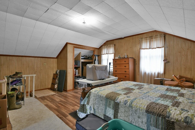 bedroom featuring vaulted ceiling, wood finished floors, baseboards, and wooden walls