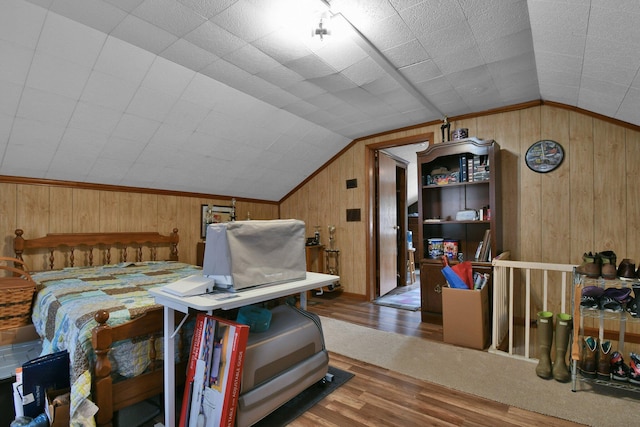 bedroom with vaulted ceiling, wooden walls, and wood finished floors