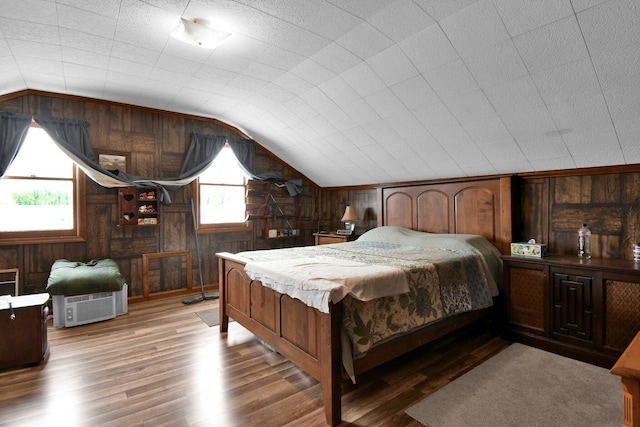 bedroom featuring lofted ceiling, wood finished floors, and wood walls