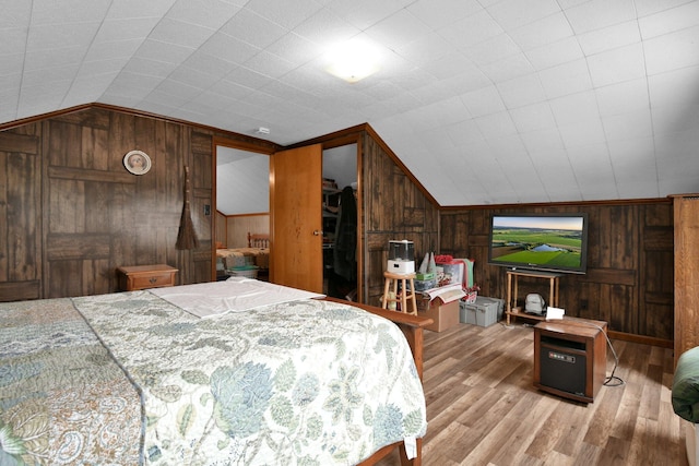 bedroom with vaulted ceiling, wood finished floors, and wooden walls