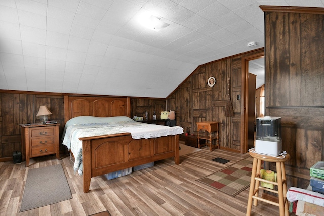 bedroom featuring lofted ceiling, wood walls, and light wood-type flooring