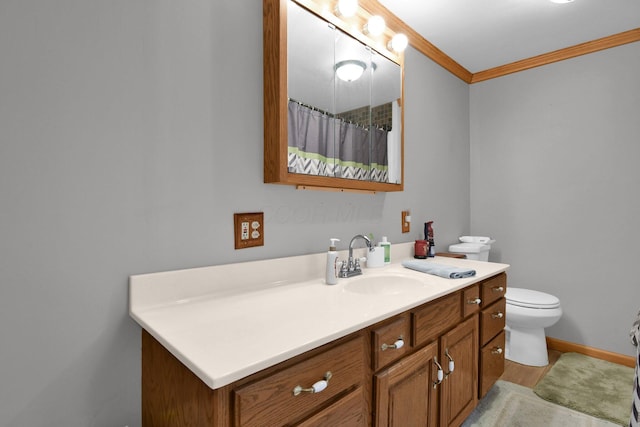 bathroom with toilet, wood finished floors, crown molding, baseboards, and vanity