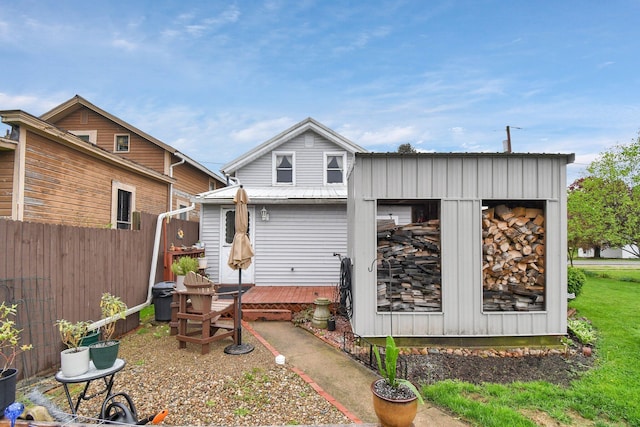 rear view of house with a deck, an outdoor structure, metal roof, and fence