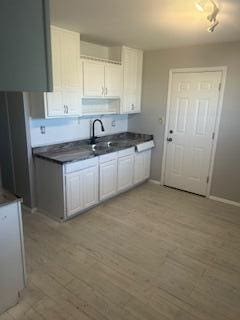 1621 Burley Dr, Columbus, OH 43207 - kitchen with dark countertops, white cabinets, light wood-type flooring, and a sink