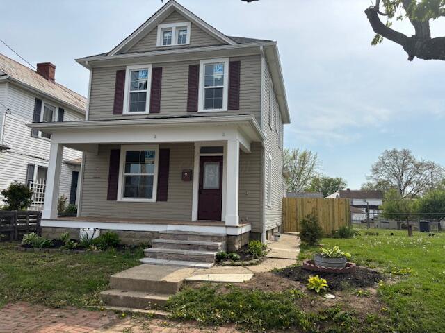 american foursquare style home featuring covered porch and fence