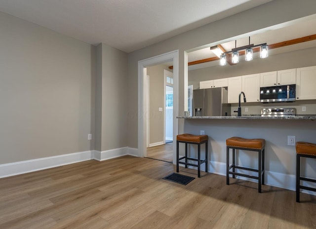 730 Forest Rose Ave, Lancaster, OH 43130 - kitchen featuring stainless steel appliances, a breakfast bar area, light wood-type flooring, white cabinetry, and dark stone countertops