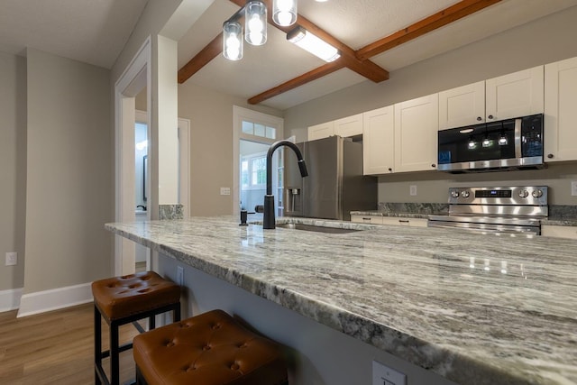 730 Forest Rose Ave, Lancaster, OH 43130 - kitchen featuring appliances with stainless steel finishes, a sink, a breakfast bar, white cabinetry, and wood finished floors