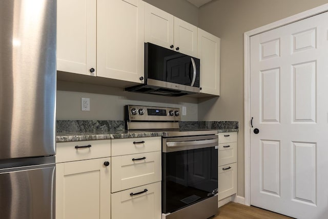730 Forest Rose Ave, Lancaster, OH 43130 - kitchen featuring appliances with stainless steel finishes, white cabinetry, light wood finished floors, and dark stone countertops