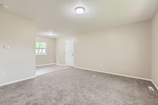 unfurnished room featuring carpet floors, baseboards, a textured ceiling, and a smoke detector