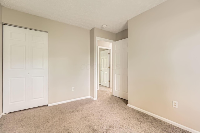 unfurnished bedroom with carpet floors, baseboards, a closet, and a textured ceiling
