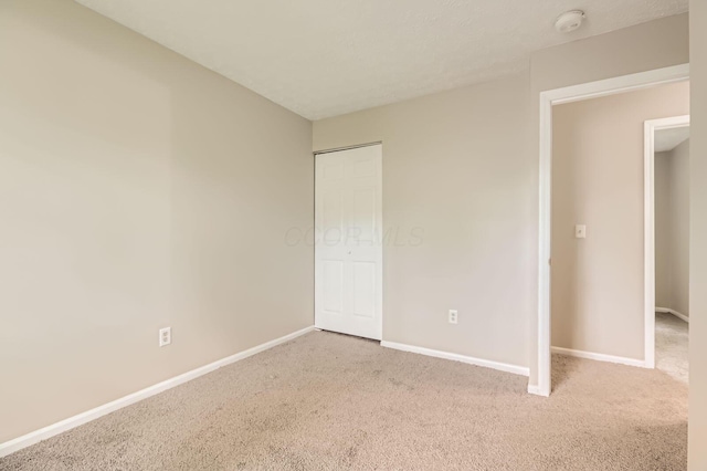 unfurnished bedroom with carpet, baseboards, and a closet
