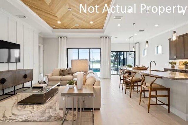living area featuring a tray ceiling, crown molding, visible vents, and recessed lighting