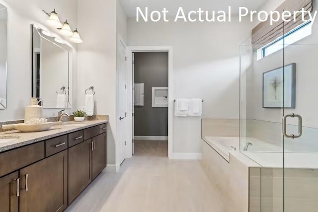 bathroom featuring double vanity, a stall shower, a sink, a bath, and baseboards