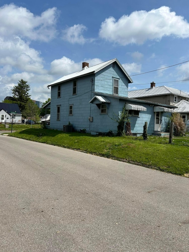 1218 W Mulberry St, Lancaster, OH 43130 - view of property exterior with central air condition unit, metal roof, a chimney, and a lawn