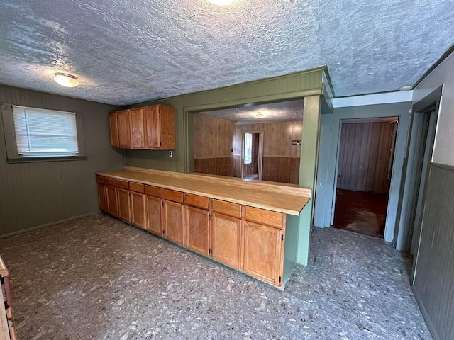 1218 W Mulberry St, Lancaster, OH 43130 - kitchen with light countertops, a textured ceiling, wood walls, and brown cabinets