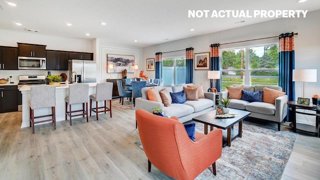 living room with visible vents, light wood-style flooring, and recessed lighting