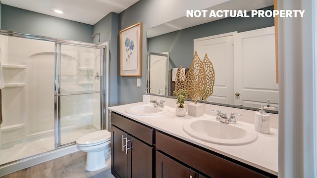 bathroom with double vanity, toilet, a stall shower, and a sink
