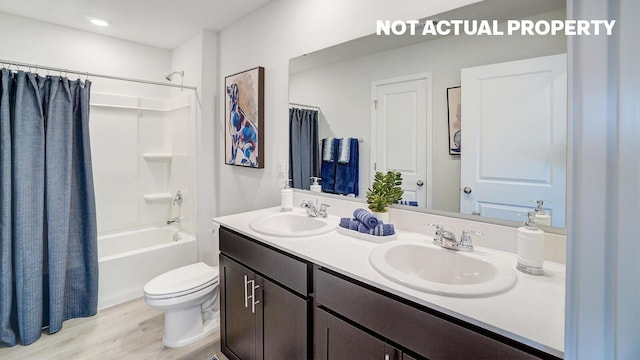 full bathroom featuring toilet, double vanity, a sink, and shower / bathtub combination with curtain