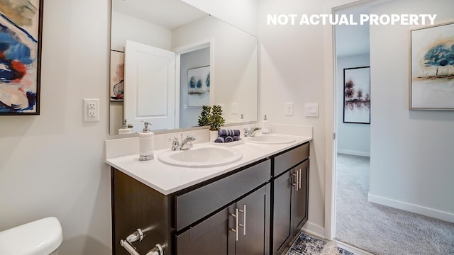 full bathroom with a sink, double vanity, toilet, and baseboards
