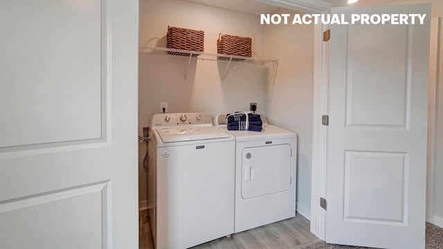 clothes washing area featuring washing machine and clothes dryer, light wood finished floors, and laundry area