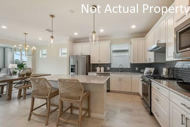 kitchen featuring a sink, stainless steel appliances, under cabinet range hood, decorative backsplash, and a center island