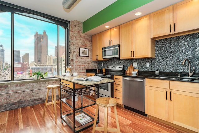 kitchen featuring a sink, stainless steel appliances, light brown cabinets, and decorative backsplash