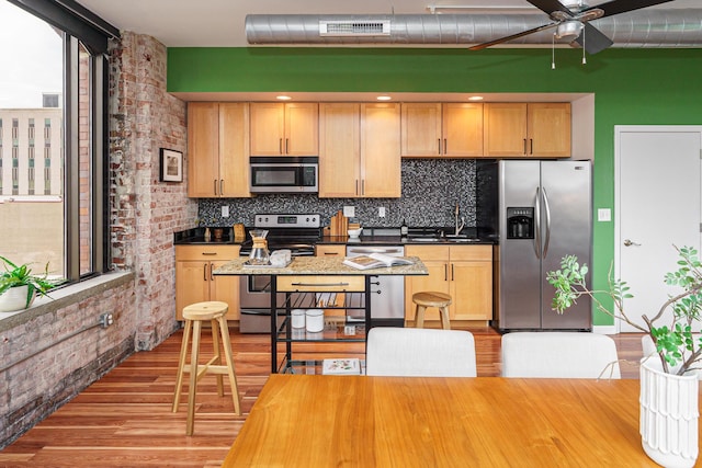 kitchen with light wood finished floors, stainless steel appliances, ceiling fan, and light brown cabinetry